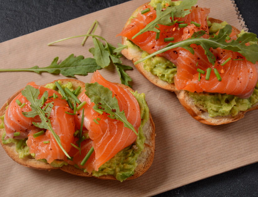 Whole grain bread with avocado paste and salmon, rocket leaves.