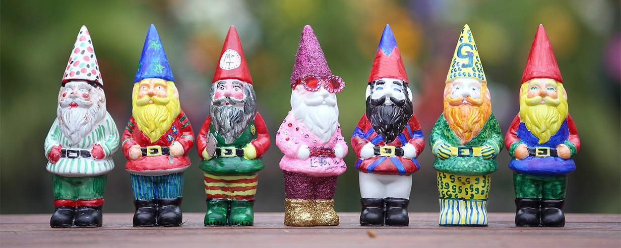 A collection of garden gnomes arranged side-by-side on a wooden table