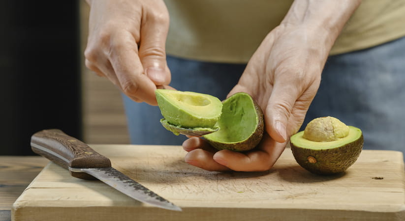 Close up of some male hands preparing avocado on a wooden chopping board