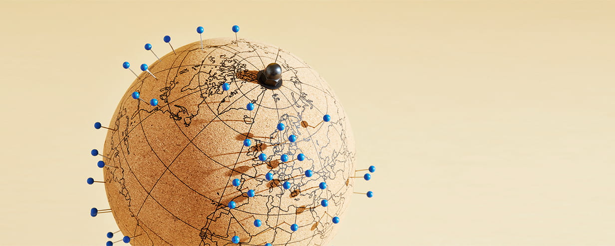 A globe with blue pins stuck into various travel destinations