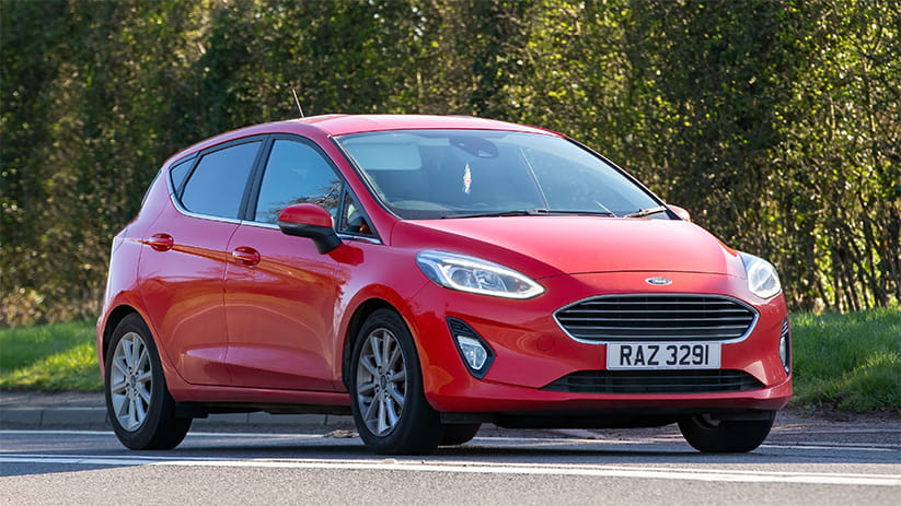 A bright red Ford Fiesta parked in front of some trees