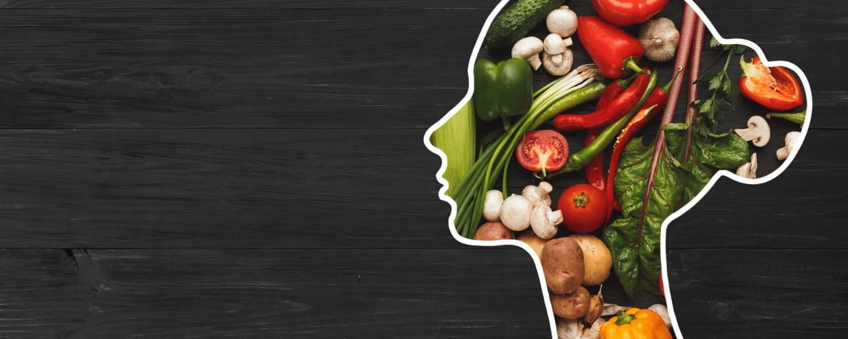 An outline of a woman's head filled with healthy food on a black background