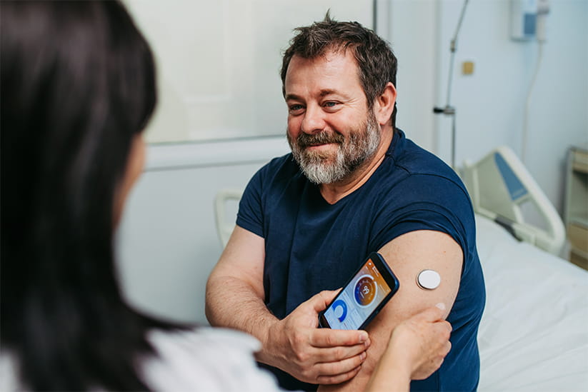 Doctor teaching diabetic patient how to use a continuous glucose monitor with a smartphone app