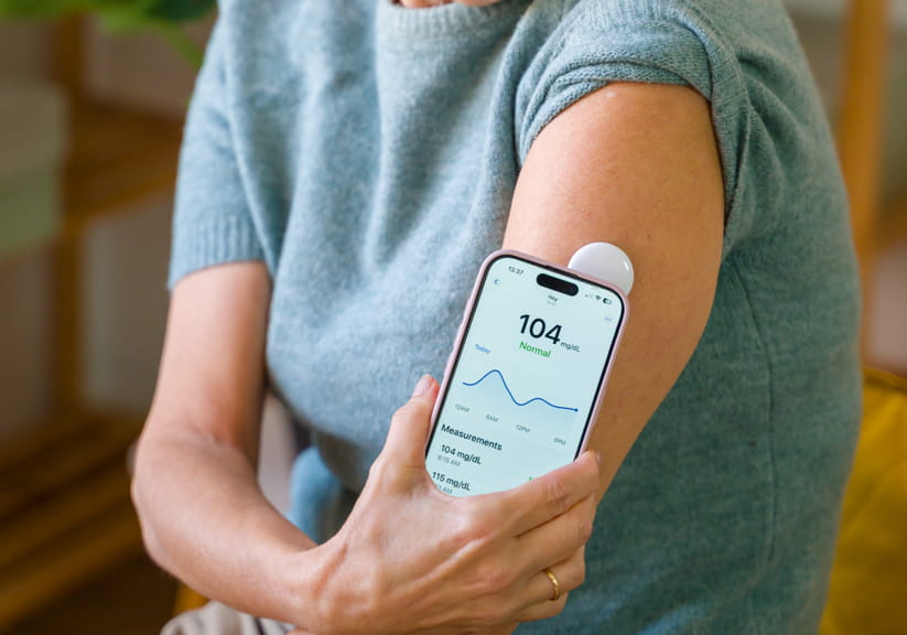 A woman holding up a glucose monitor to her arm