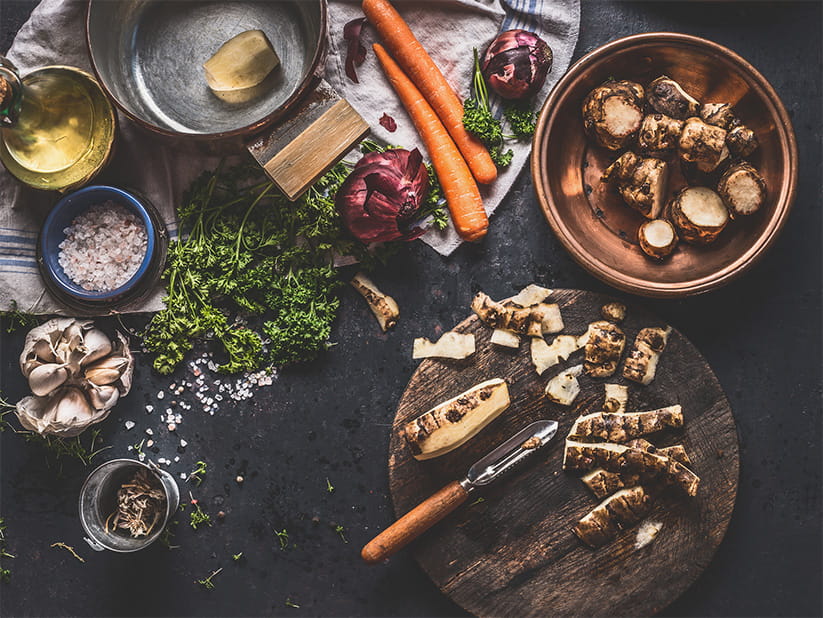 Cooking preparation of Jerusalem artichokes on dark rustic kitchen table, top view