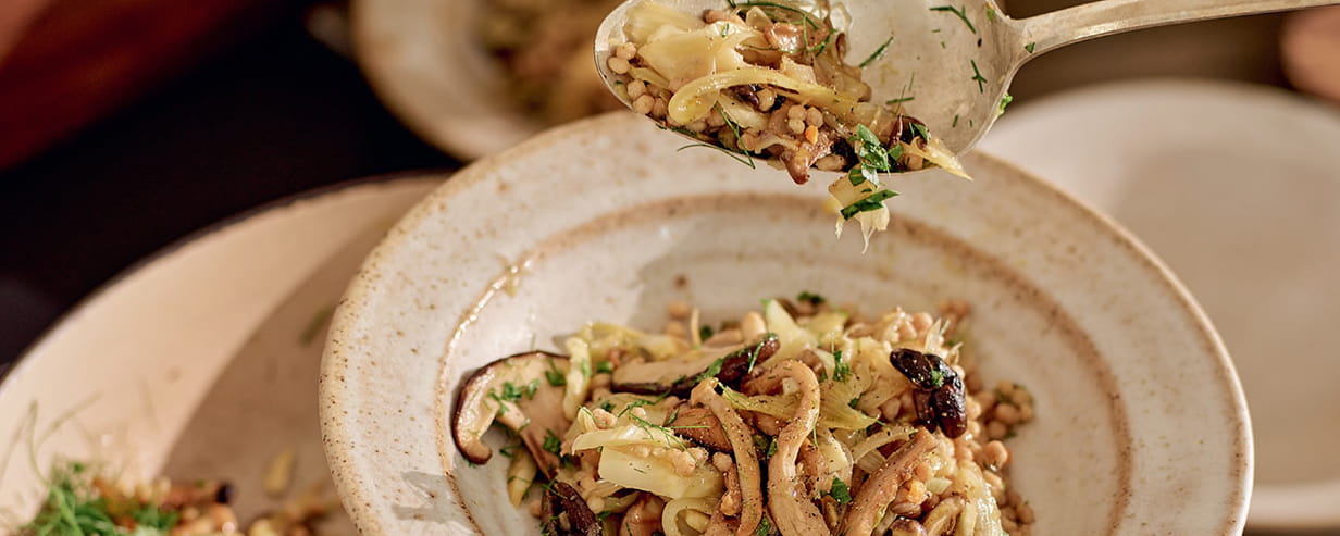 Lemony Mushroom and Fennel Couscous being spooned out of a bowl