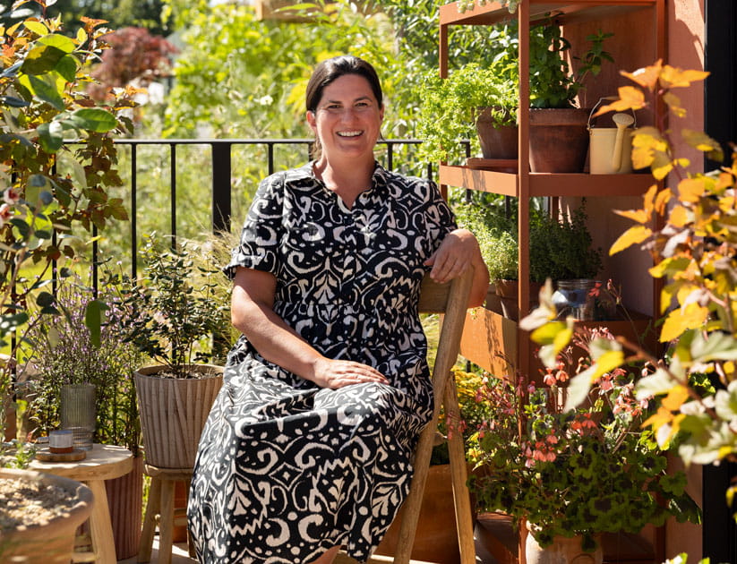 Katerina Kantalis sitting on a chair surrounded by plants in pots