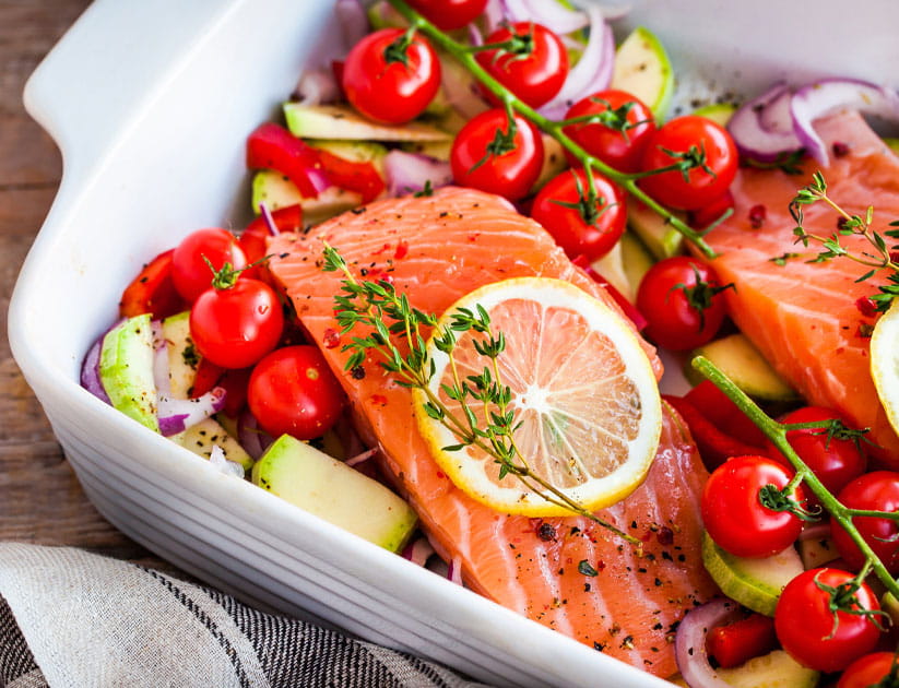 Raw fresh delicious salmon, cherry tomatoes, onion, zucchini, pepper and lemon in pan, ready to cook