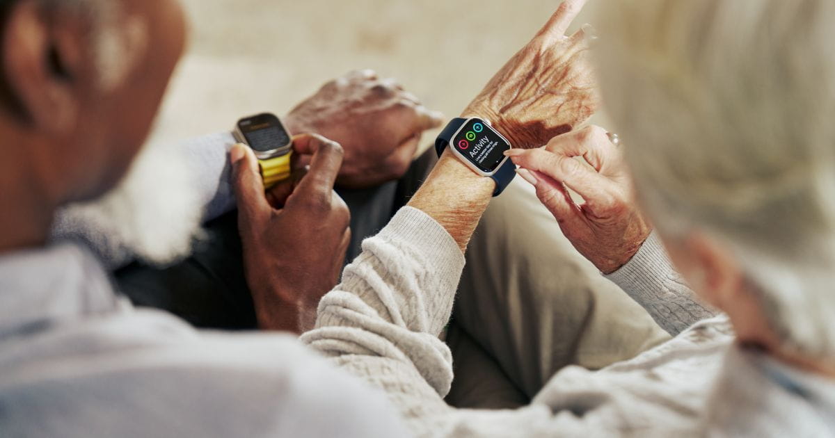 An overhead shot of a couple looking at their fitness trackers on their wrists