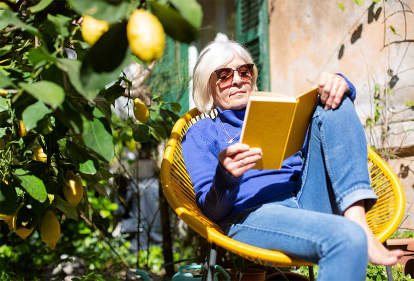  Senior woman relaxing in the garden with a book