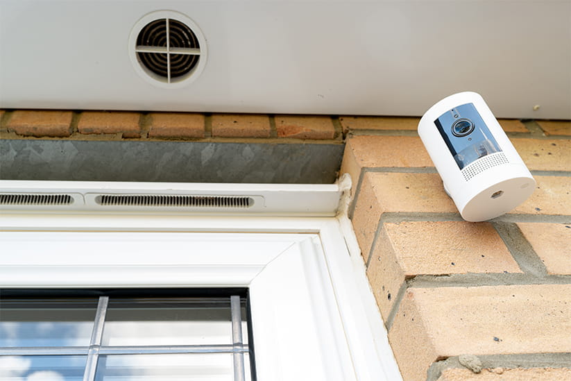 Newly installed, battery-powered wireless security camera attached to a brick wall.