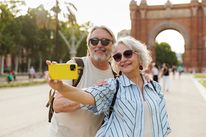 Happy senior tourist couple taking selfie in barcelona near arc de triomf