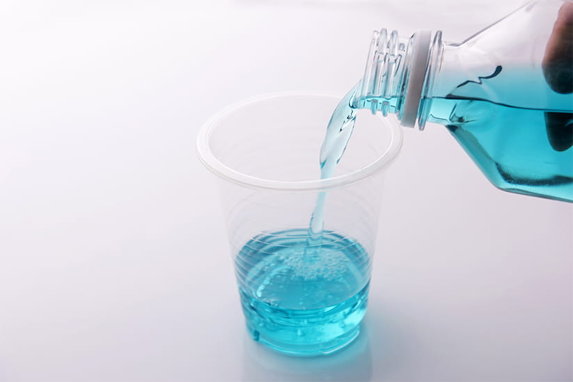Blue mouthwash being poured into a clear plastic cup