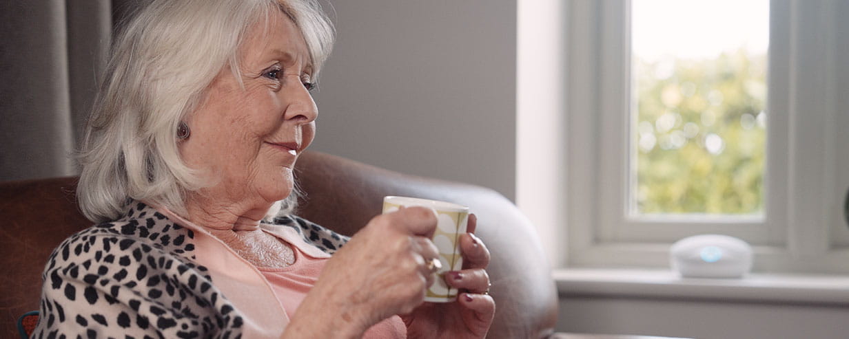 Mature woman sitting in a chair holding a mug with both hands