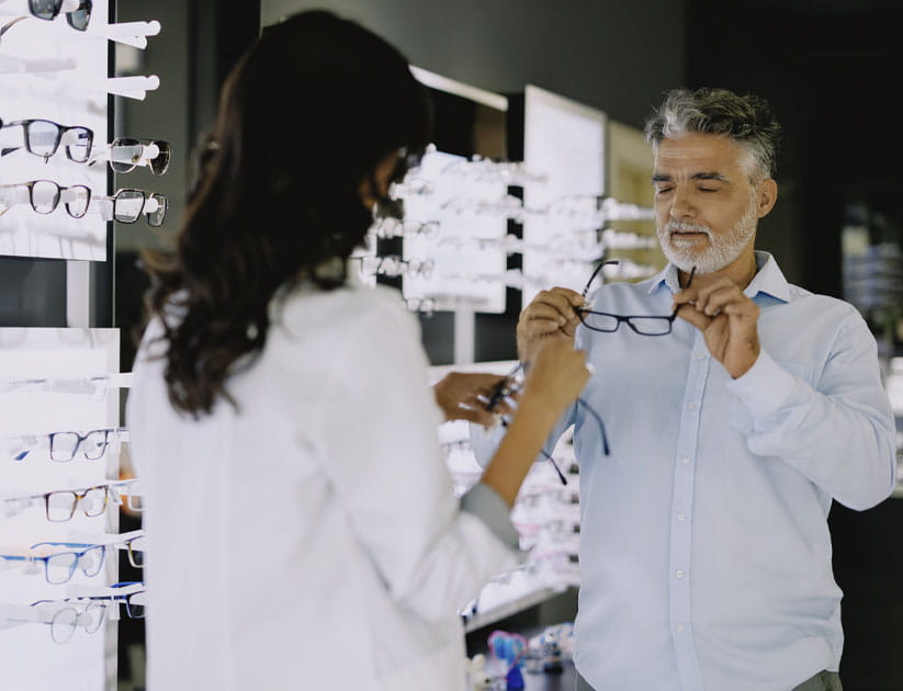 Optometrist assisting an mature male client in choosing eyeglass frames