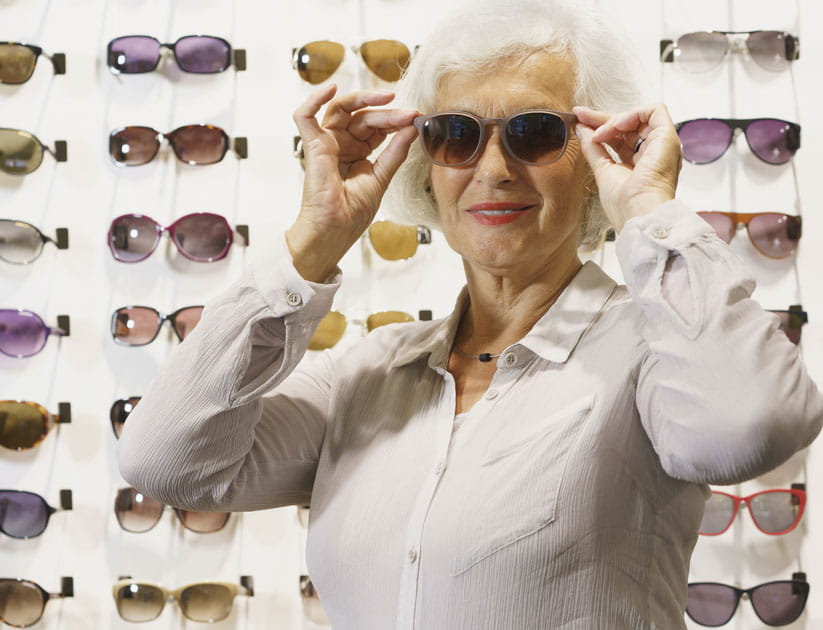 Stylish mature woman trying on good quality UV sunglasses in an opticians