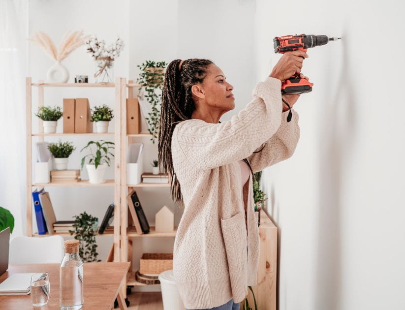 Woman using a drill on her wall