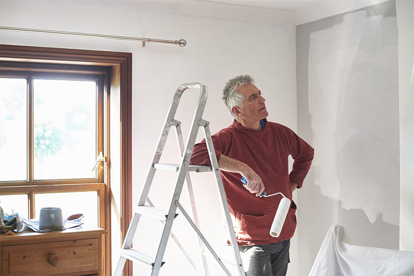 A senior man painting his bedroom