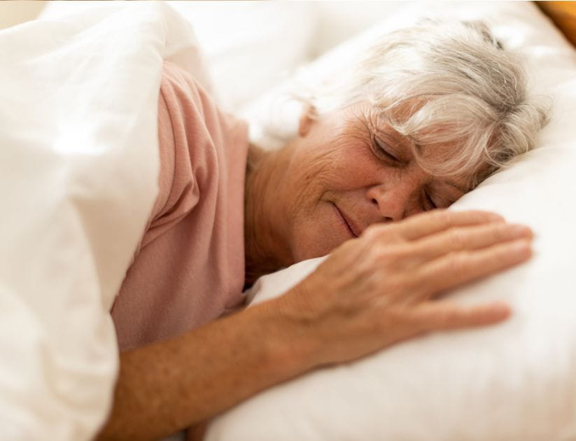 Woman on her side in a bed and looking comfortable