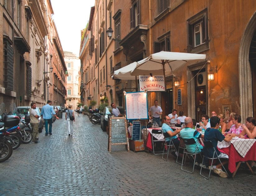 Lantern lit street in Rome with people eating at a restaurant 