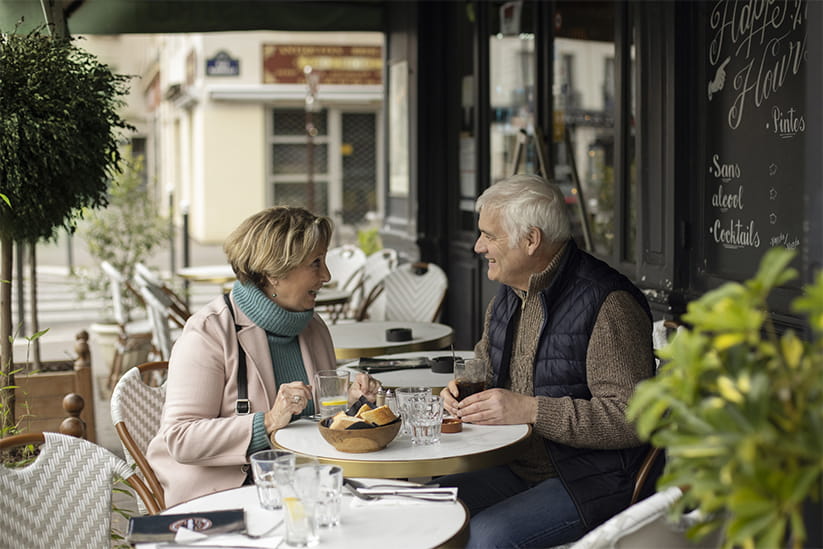 An elderly couple having a good time on the terrace of a Parisian cafe