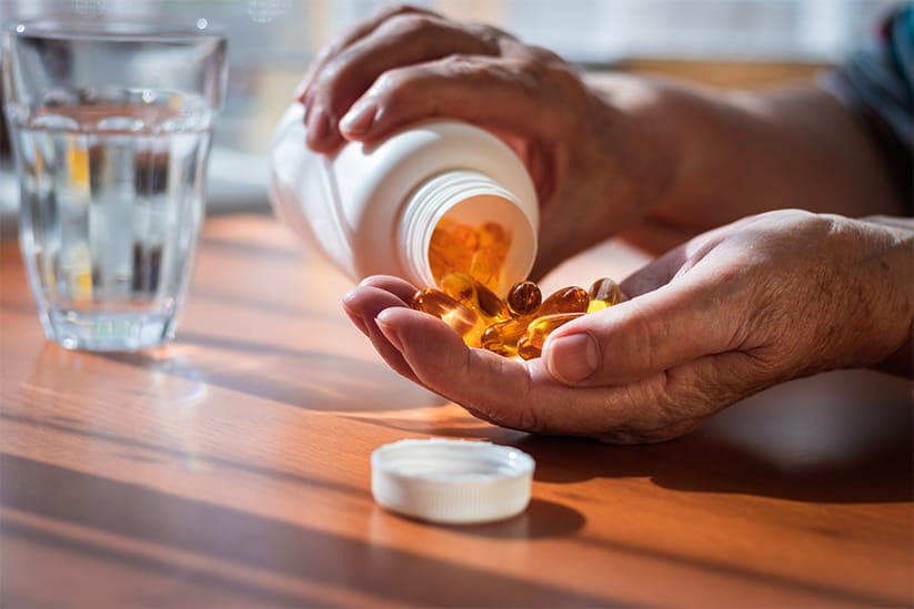 Senior woman taking omega 3 pills from bottle