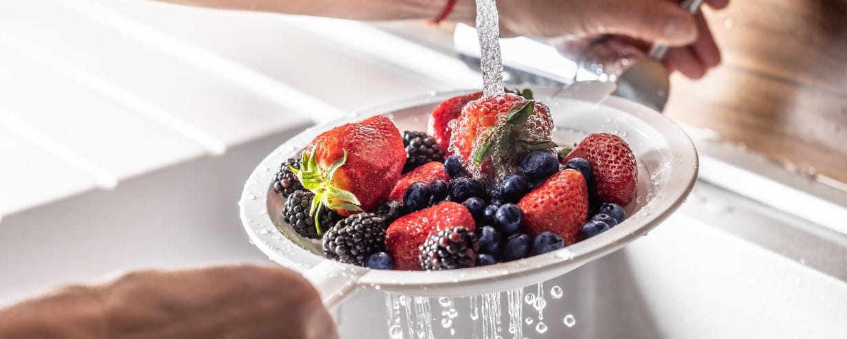 Berries including blackberries and strawberries being washed in the sink