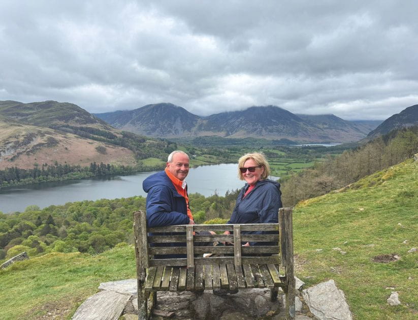 A photograph of Paul and Janet sitting on a bench with a nice view of the countryside