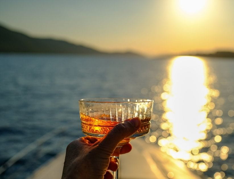 Woman holding cocktail glass during sunset yacht cruise on the sea
