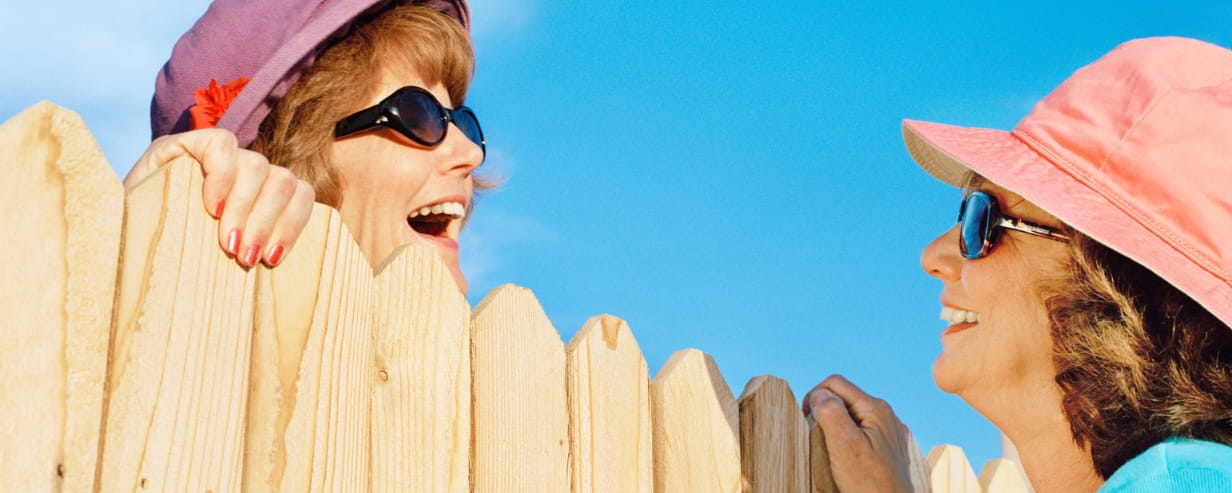 Two women neighbours chatting over a garden fence