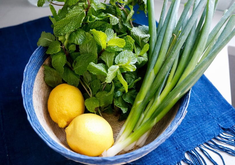 Herbs in a bowl with lemons and spring onions