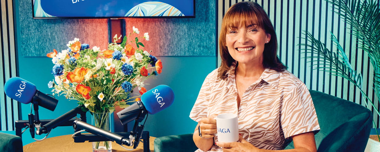 Lorraine Kelly in the Saga Experience is Everything Podcast studio, smiling at the camera holding a Saga branded coffee mug