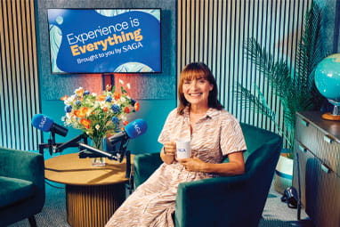 Lorraine Kelly in the Saga Experience is Everything Podcast studio, smiling at the camera holding a Saga branded coffee mug