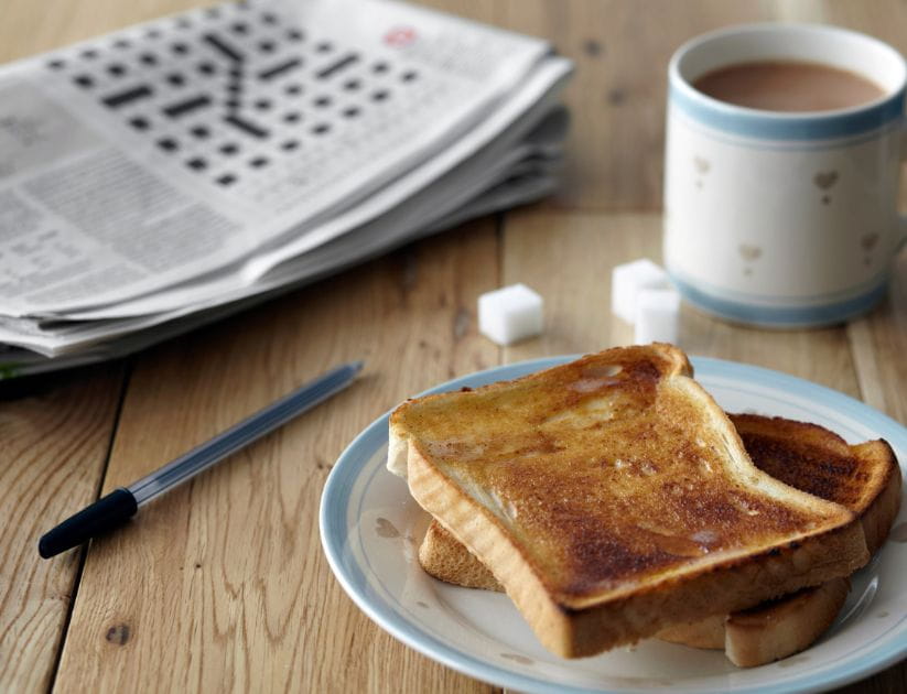 Crossword puzzle with a toast and a cup of tea next to it