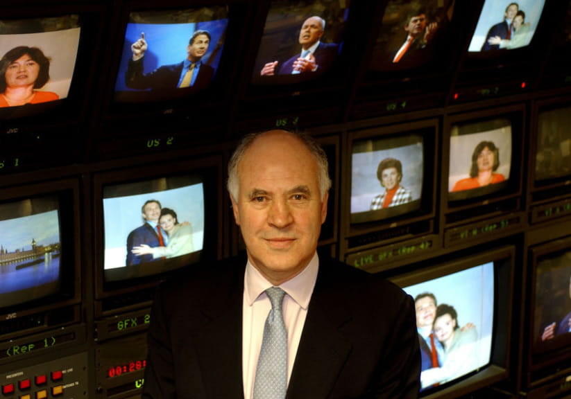 BBC interviewer Michael Cockerell in front of a wall of TV screens