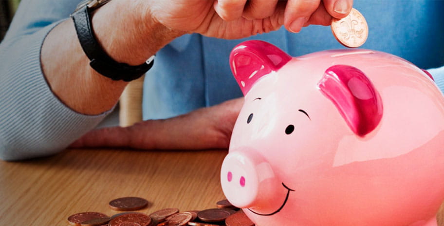 A woman puts pennies into a pink piggy bank