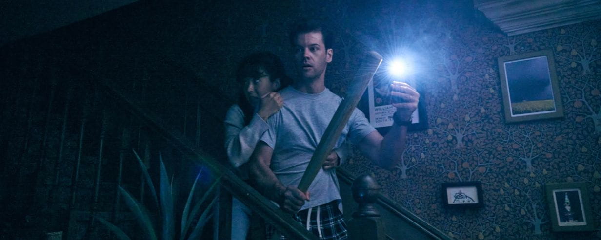 A shot of the two main protagonists of the play on a dark stairwell holding a torch 