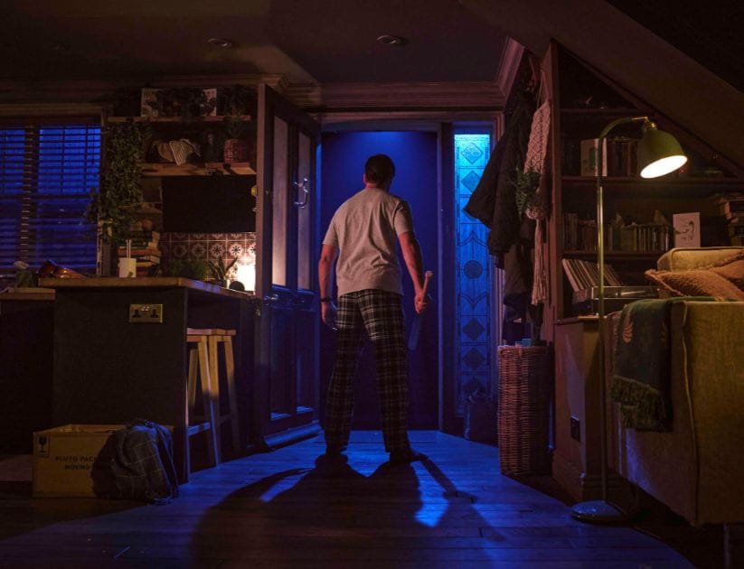 A man facing an ominous open door holding a baseball bat 