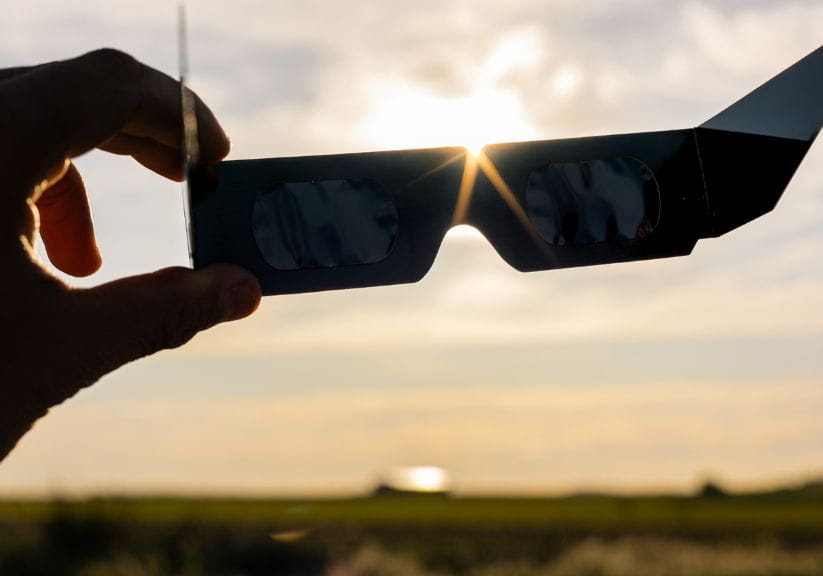 A person holds a pair of special solar eclipse glasses