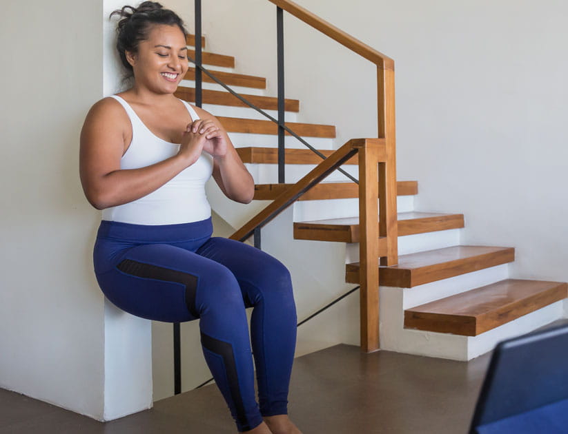 Portrait a woman doing wall sit exercise in her living room