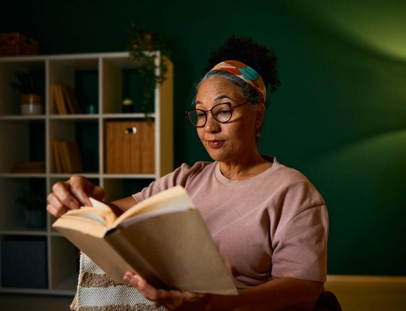 Senior woman reading a book at home in the evening