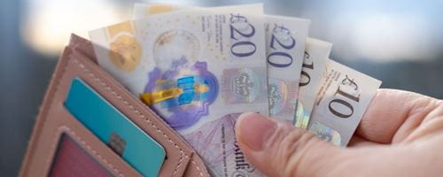 Person holding a wallet with cash and card showing
