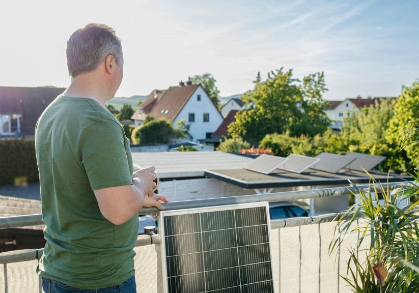 A man stands on his balcony overlooking his plug in solar panels
