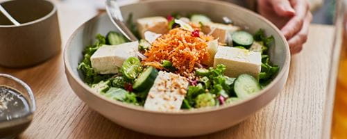 woman enjoying lunch containing tofu at a vegan cafe.