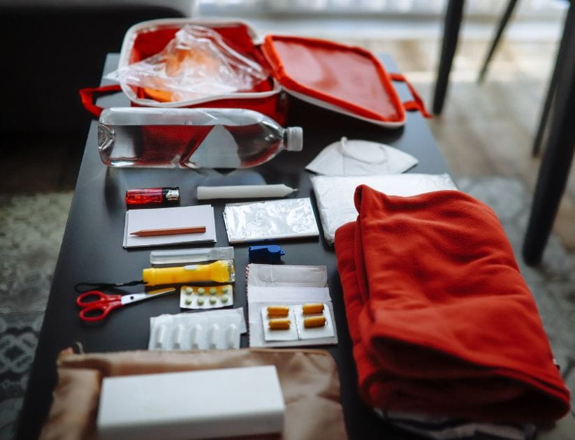 Prepping essentials: water, protective gear, whistle, raincoat, and tools for emergencies