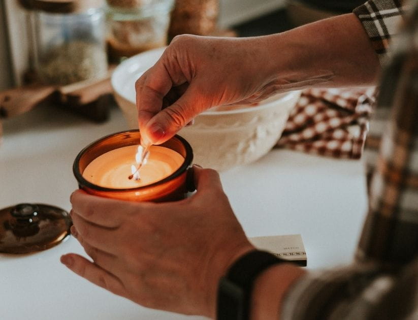 Woman lighting a candle while preparing a meal at home