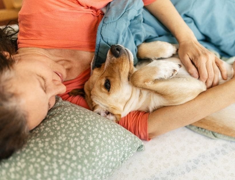 Mature adult woman lying on bed in bedroom with her dog