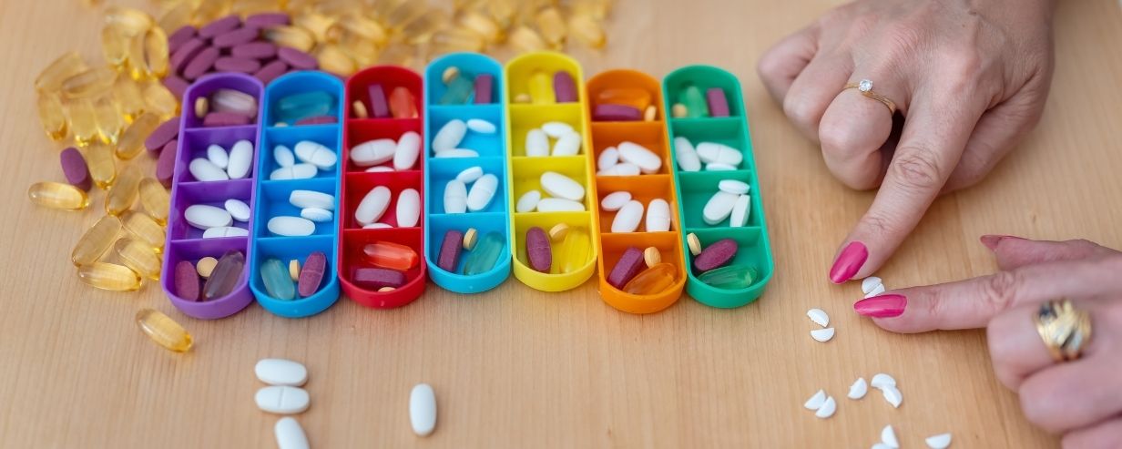 A lady splits a white pill in half with her fingers to organize them for medication