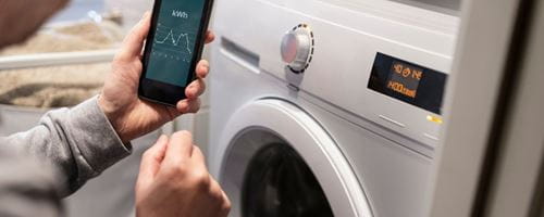 Someone holding up a smart meter app while their washing machine is running