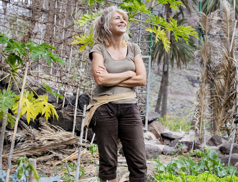 mature woman in her garden admiring the plants